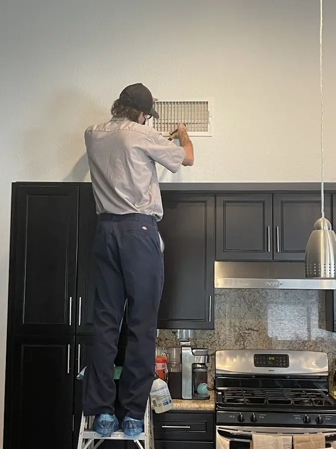Technician inspecting an air vent during HVAC service in Ocean